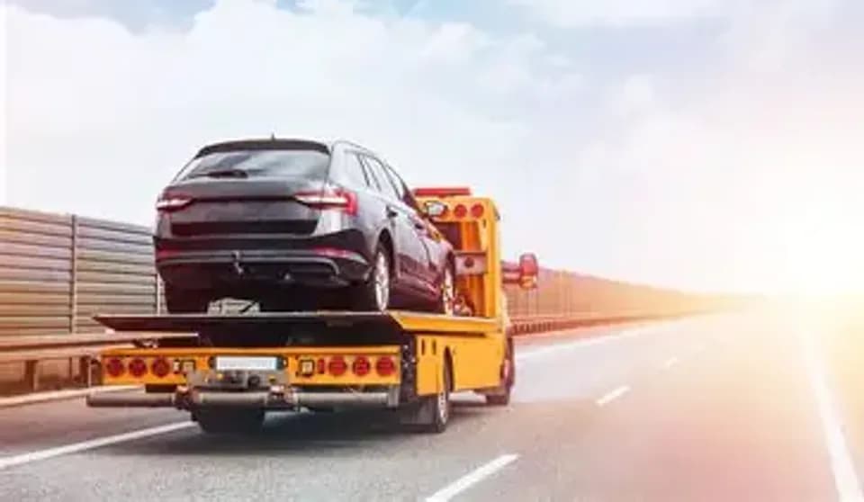 Yellow car carrier transporting a vehicle on the highway