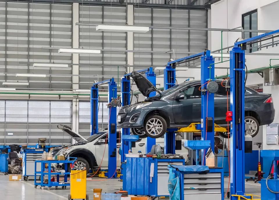 Vehicles elevated on blue lifts in a pre-shipment inspection garage